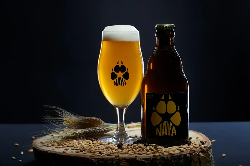 Glas en flesje Naya, blond bier met een wolvenpoot op het etiket