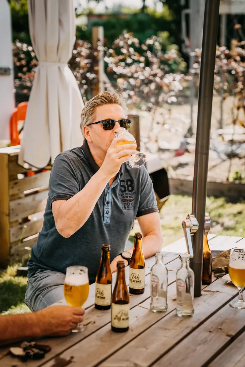 Man geniet van een glas bier op het terras