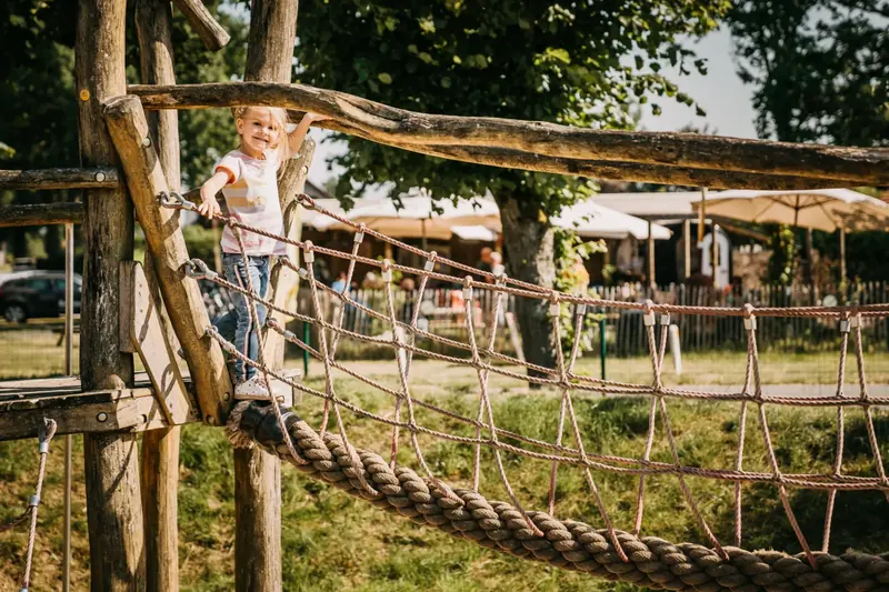 Kind op de touwbrug van de speeltuin