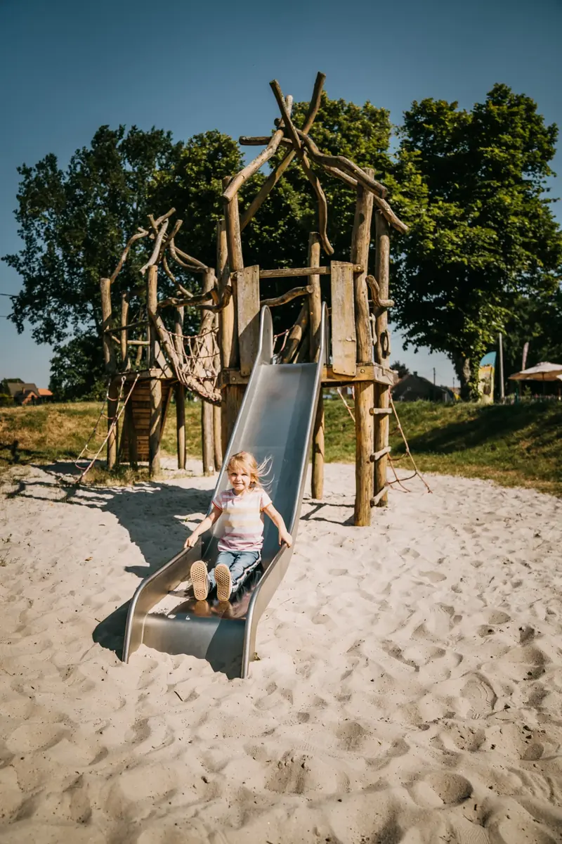 Kind op de glijbaan in de zandbak